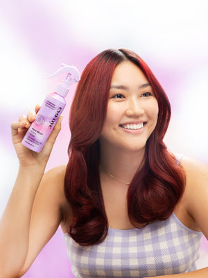 Model holding Eva NYC's Mane Magic 10-in-1 Hair Primer Heat Protectant for Hair